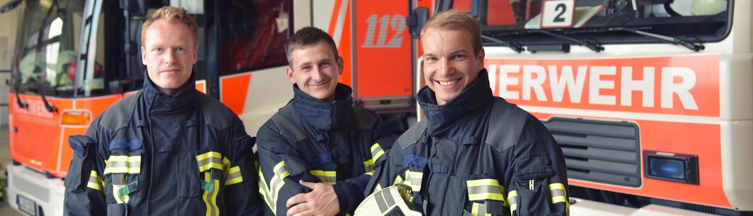 Feuerwehrteam vor Einsatzfahrzeugen – Feuerwehr, Brandschutz, Gefahrenabwehr und vorbeugender Brandschutz